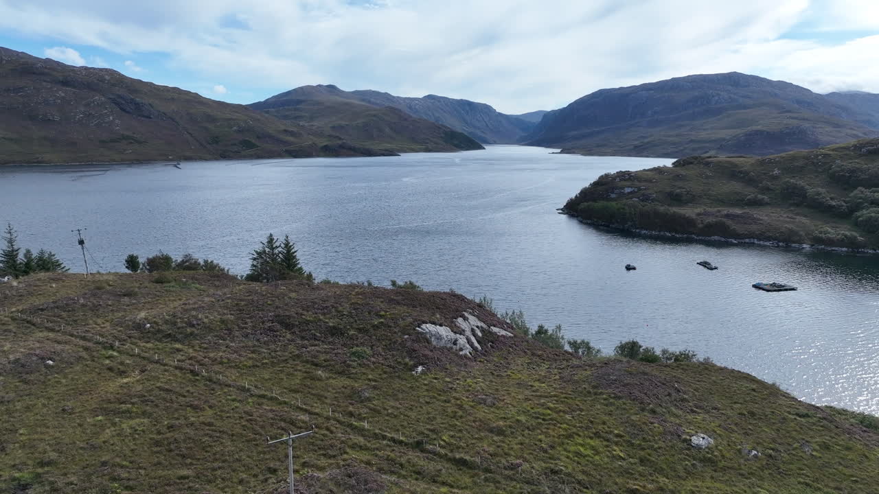 Aerial view of Loch Laxford in the Scottish Highlands, showing calm water, rocky hills, and distant peaks. Captured by drone on a bright day, showcasing the wild natural beauty of northwest Scotland