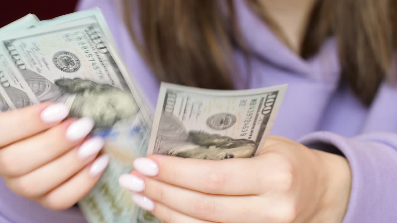 primer plano de las manos de una mujer sosteniendo una pila de billetes de 100 dólares. una mujer cuenta dinero en efectivo dinero americano. enfoque selectivo dinero de papel americano con una denominación de 100 dólares