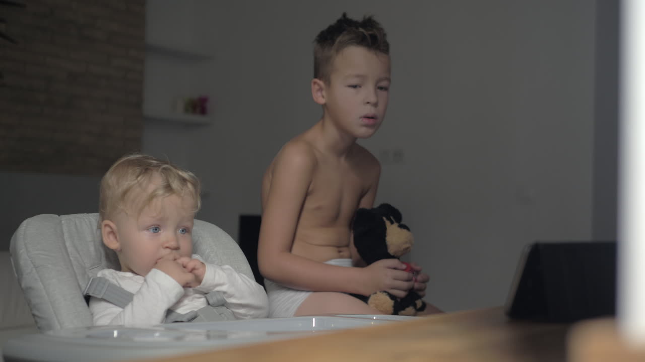 잠자는 소년과 그의 아기 여동생은 아침에 태블릿 pc에서 만화를 보고 있습니다.