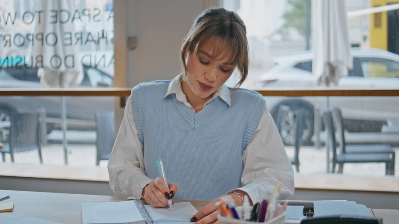 Focused lady flipping pages at remote workplace closeup. Girl writing notes