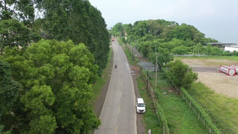 aerial view of a road through a lush green landscape with industrial area