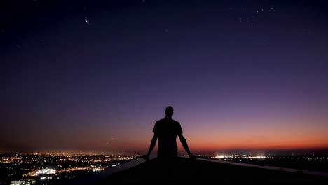 silhouette of a man on a rooftop at twilight, overlooking the city