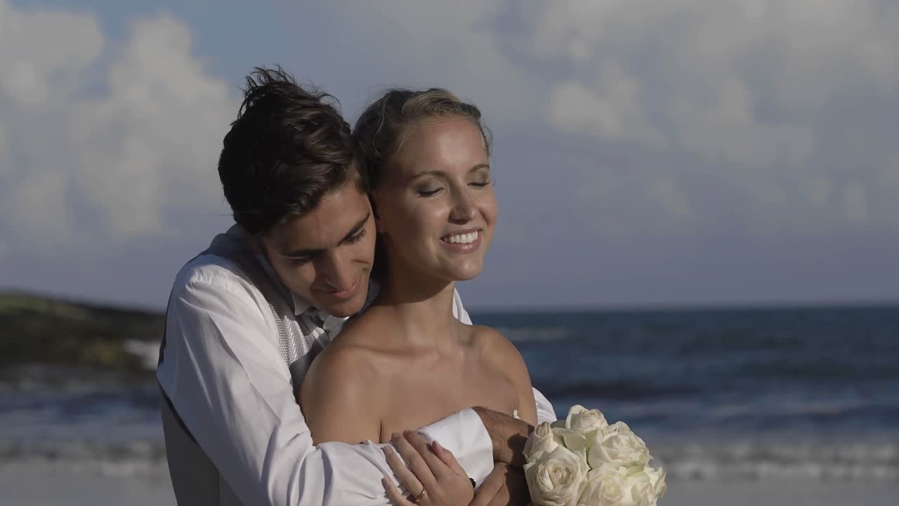 recién casados sonrientes abrazados en la playa
