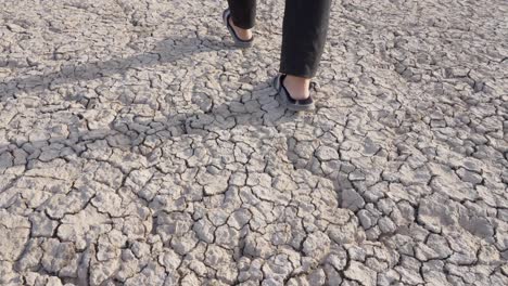 fotografía de alto ángulo de manos de pies masculinos con zapatillas que caminan en un suelo extremadamente seco