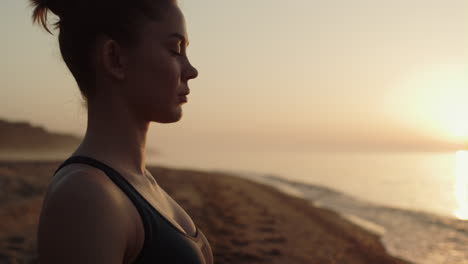 Profile-sportswoman-making-meditation-exercise-on-beach-cposeup.-Harmony-concept