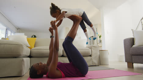 happy african american mother and daughter doing yoga exercise at home