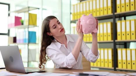 Woman holding piggy bank in office