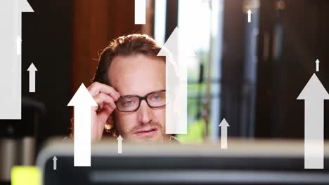 animation of moving up arrows over caucasian man working in laptop at office