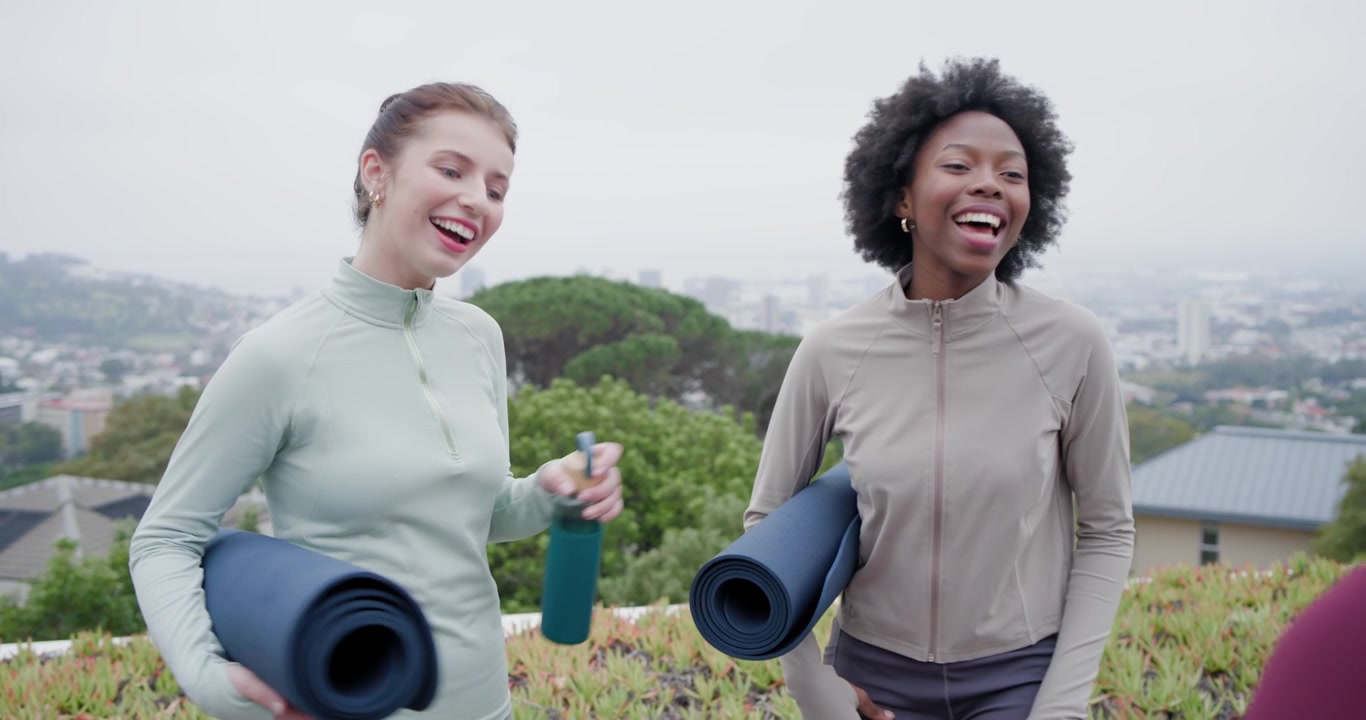 Diverse amiche in piedi sul tetto con tappetini blu navy, che salutano un'amica in arrivo prima dello yoga