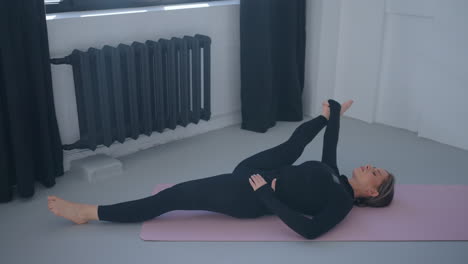 mujer estirándose en una alfombra de yoga en un estudio