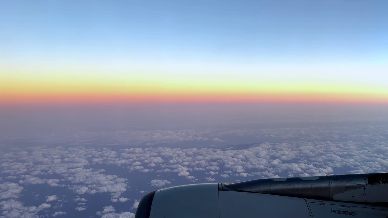 비행기 창문에서 구름 위의 해가 지는 색, 부드러운 파스텔 하늘, 조용한 여행 장면, 높은 고도 풍경