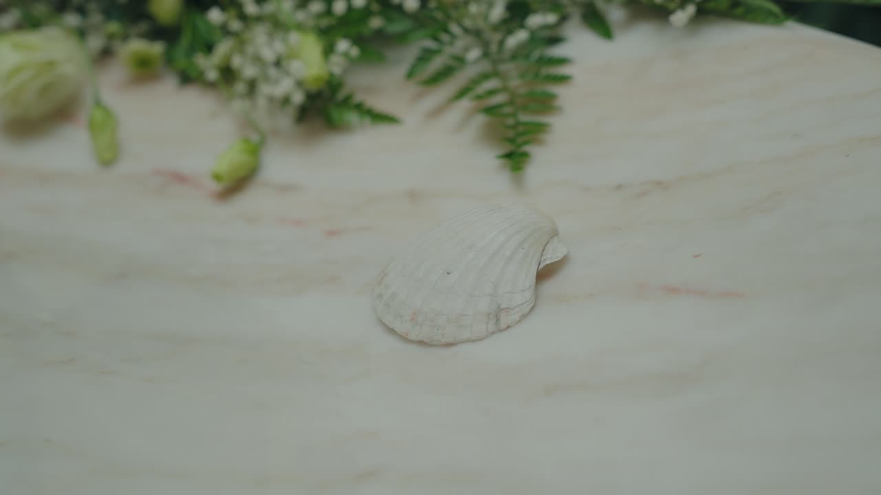 Seashell resting on marble baptismal font with flowers