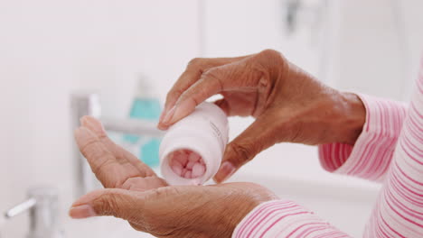 close up of senior woman in bathroom taking vitamin supplement tablets