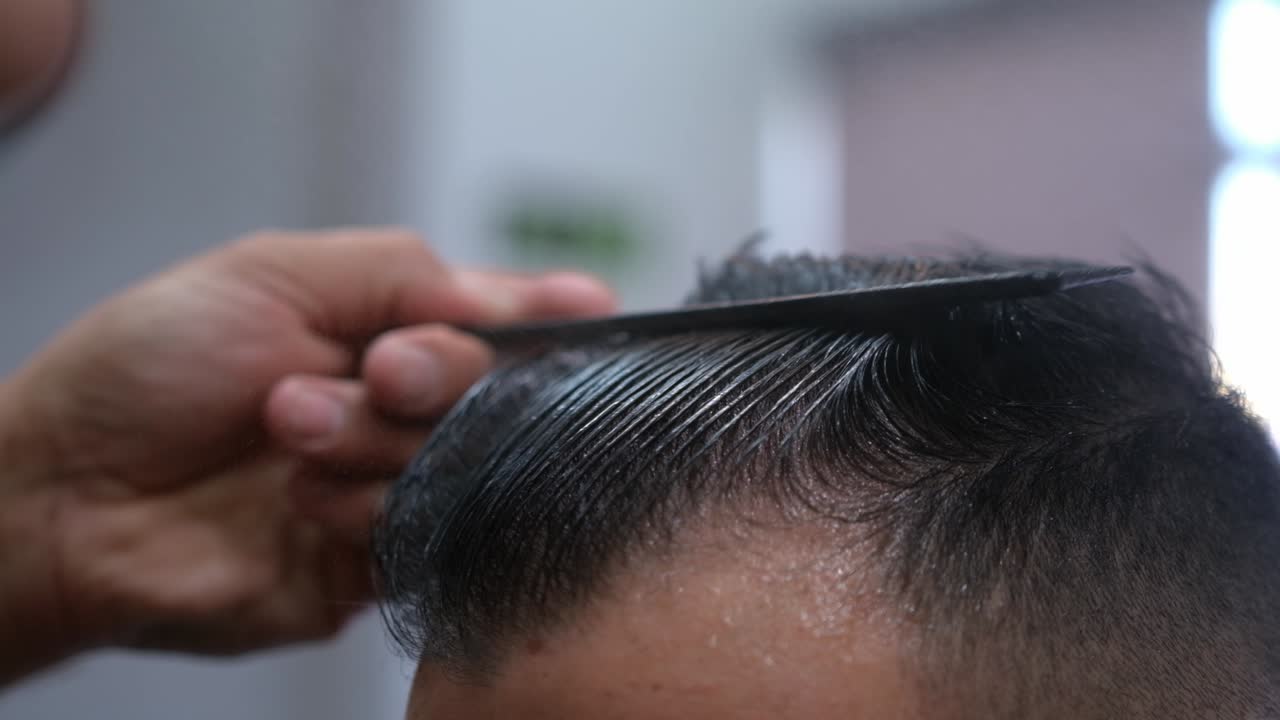 Primo piano di un barbiere che modella e sistema i capelli di un uomo
