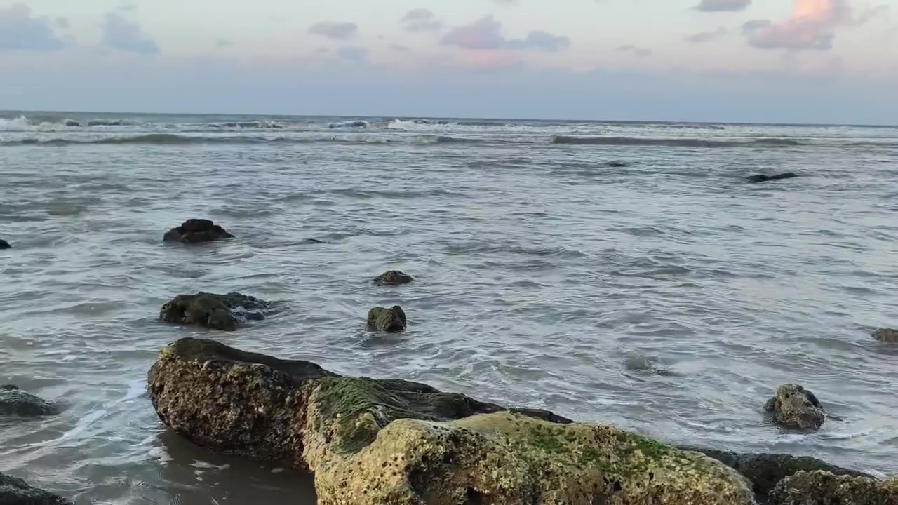 Onde delicate che si infrangono su rocce muschiose al tramonto