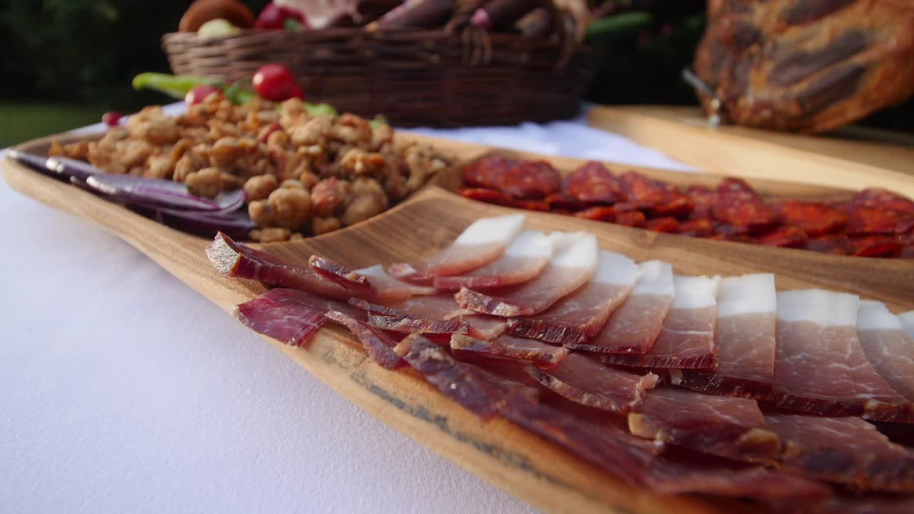 Sliced bacon, sausage and greaves served on a platter. Smoked, dried pork meat products