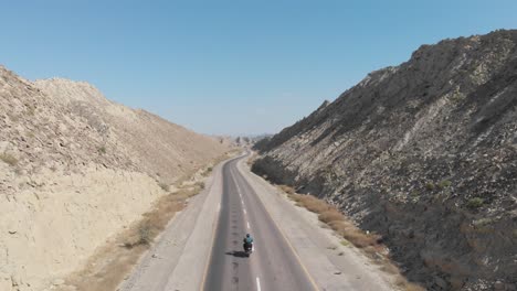 Motociclista-A-Lo-Largo-De-La-Carretera-Costera-Vacía-N10-Makran-Junto-A-Espectaculares-Formaciones-Rocosas-En-El-Parque-Nacional-Hingol