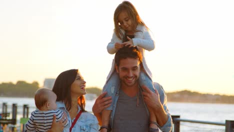 Padres-Cargando-Niños-Caminando-Junto-Al-Río-En-Manhattan