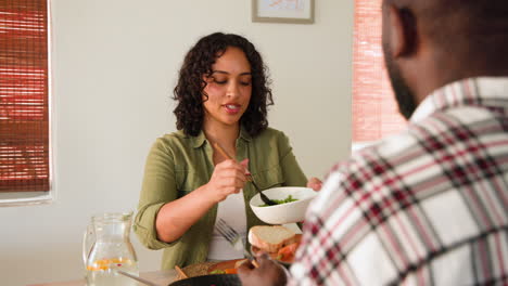 smiling multiracial couple enjoying sunday dinner meal together at home, sharing food