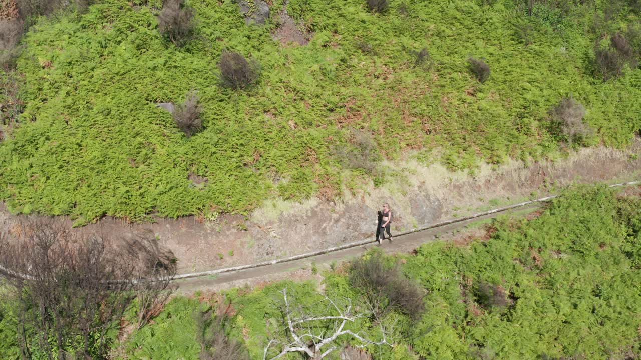 turista femenina caminando junto a un canal tradicional en las montañas de madeira