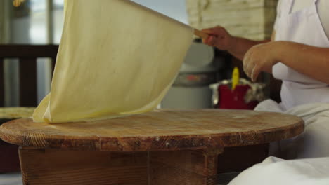 la mujer está rodando la masa con un rodillo sobre una mesa de madera