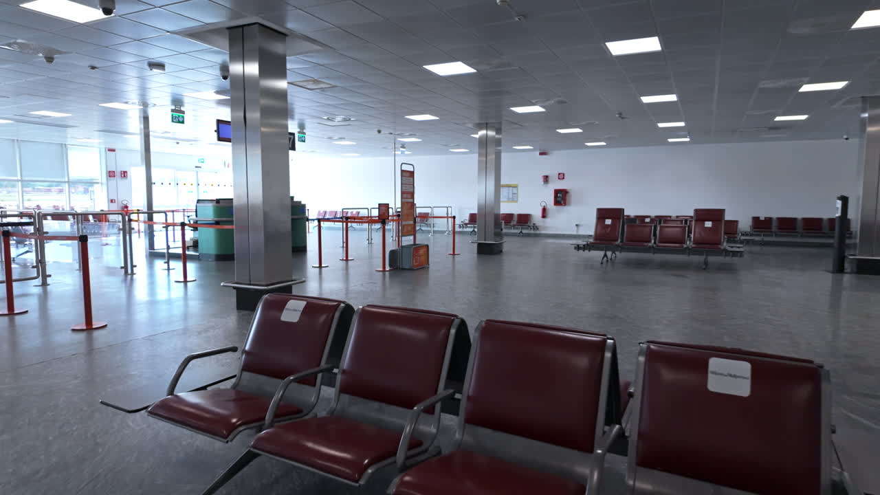Terminal Bandara Kosong dengan Deretan Kursi Merah dan Cahaya Alami Terang dari Jendela Besar