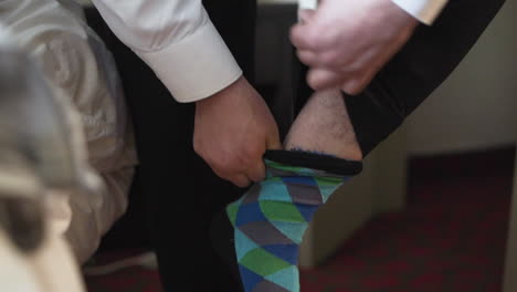 groom putting on a colourful sock in slow motion