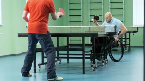 a man in a wheelchair plays ping pong. people with disabilities play table tennis. rehabilitation of the disabled. paralympic sport.