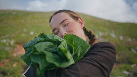 woman holding leafy vegetables on field closeup. happy girl posing with cabbage