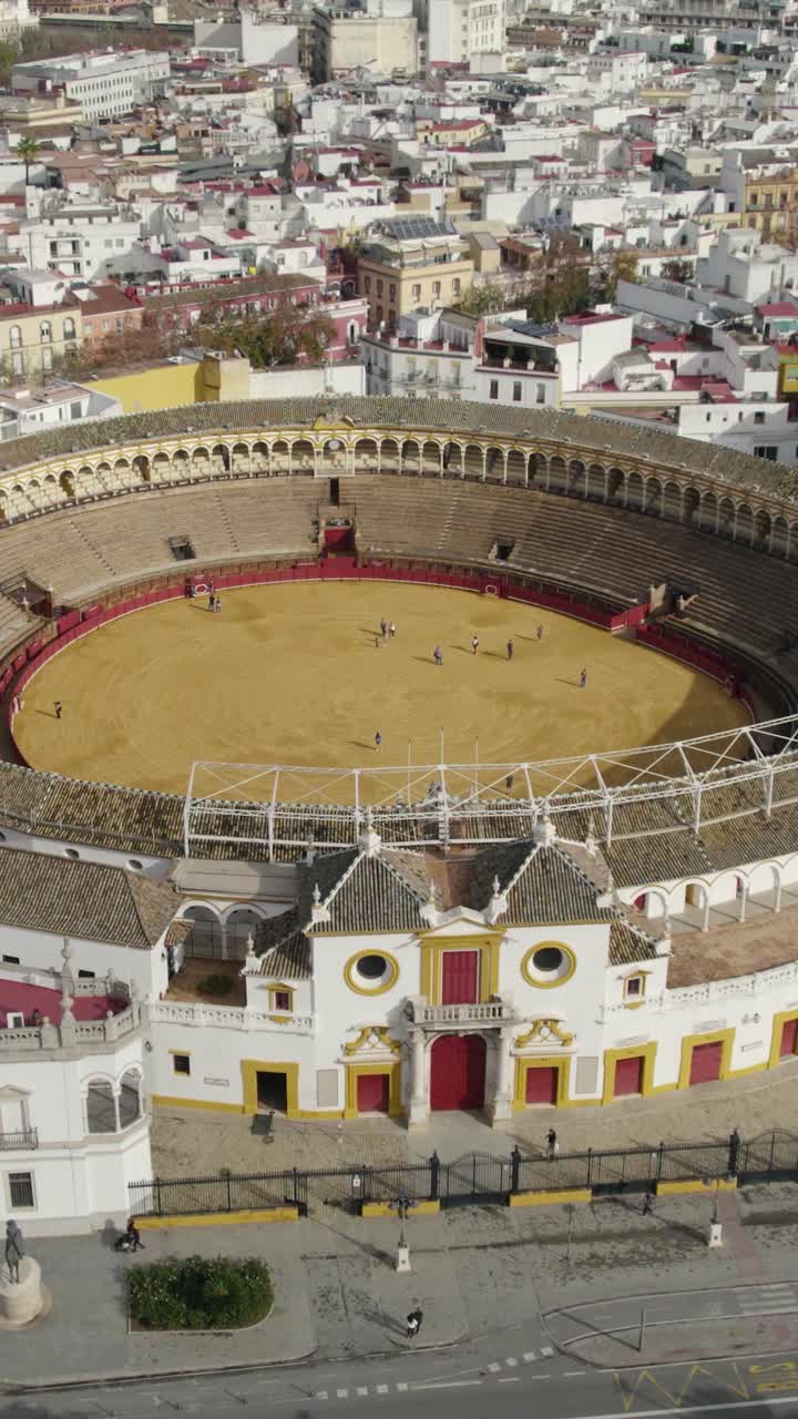 Vertikalt luftfoto som daler nedover over Plaza de Toros de la Real Maestranza, og viser frem dens sirkulære arena-struktur