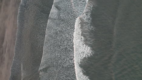 Bird's-eye-view-of-small-waves-breaking-on-shore-of-Iceland-beach