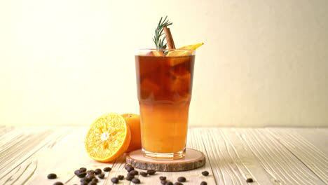 A-glass-of-iced-americano-black-coffee-and-layer-of-orange-and-lemon-juice-decorated-with-rosemary-and-cinnamon