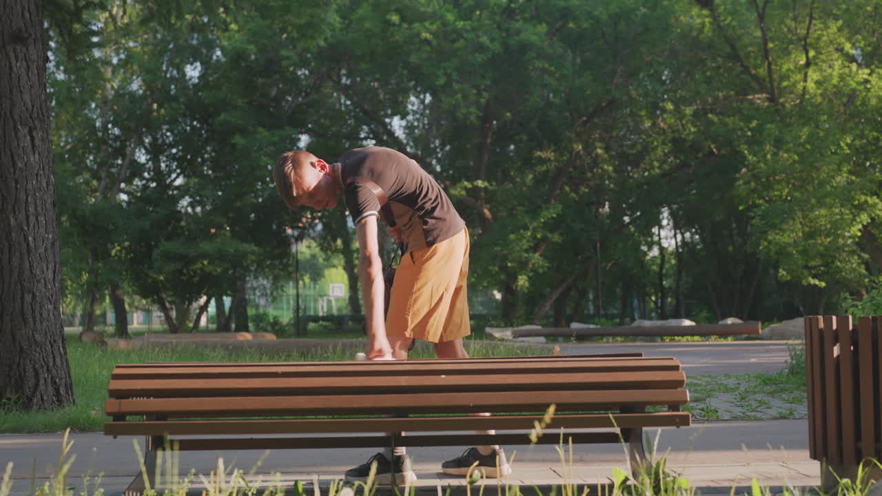 Man Searches Outdoors, Individual Looking For Item Outside, Man Peering At Object On Park Bench Carefully, Man Bends And Reaches Across Slats Searching For Something In Park Surroundings