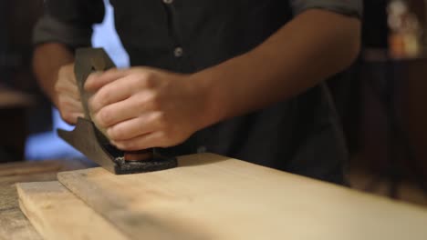 Craftsman-planing-wooden-plank-in-workshop