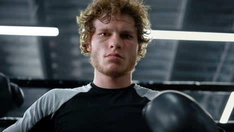 Kickboxer-Enojado-Mirando-La-Cámara-En-El-Gimnasio.-Deportista-Revisando-Guantes-De-Boxeo.