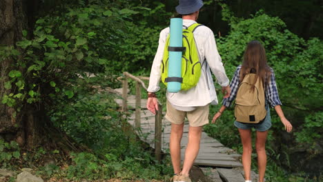 una pareja caminando por un puente de madera a través de un bosque.