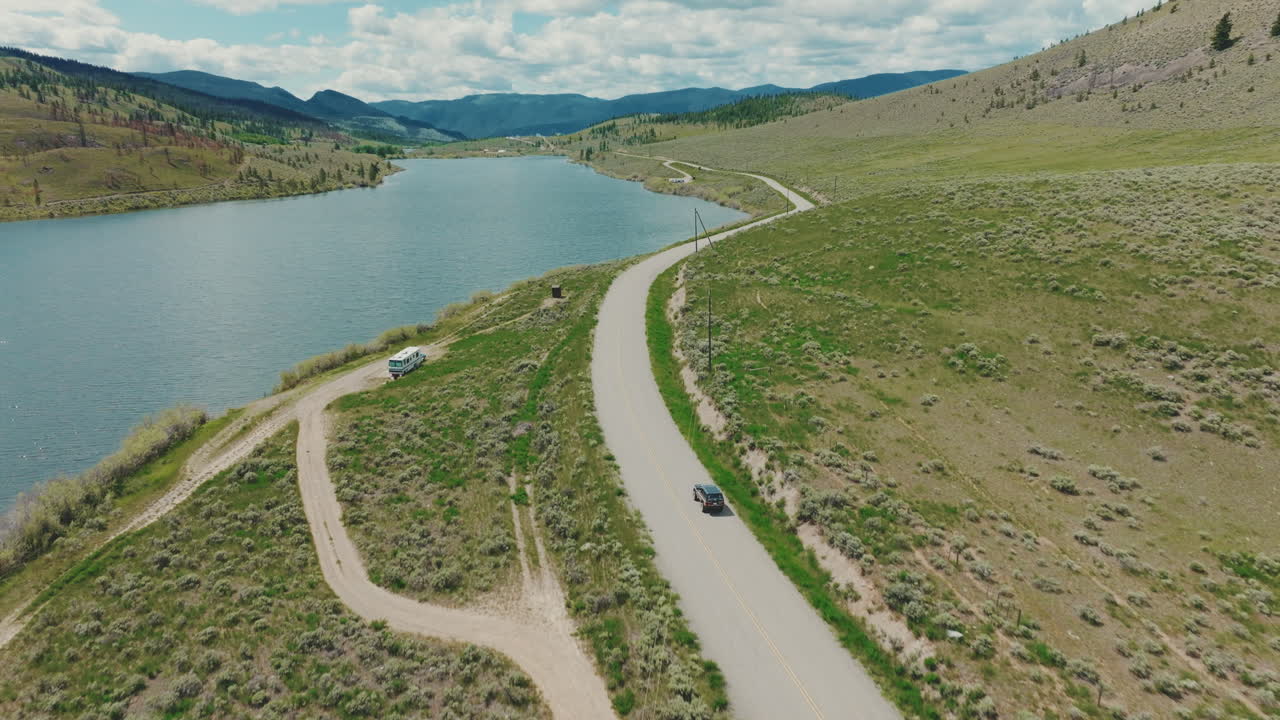 Truck drives down rural road towards a small lake