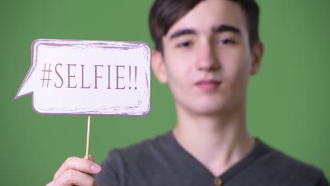 young handsome iranian teenage boy against green background