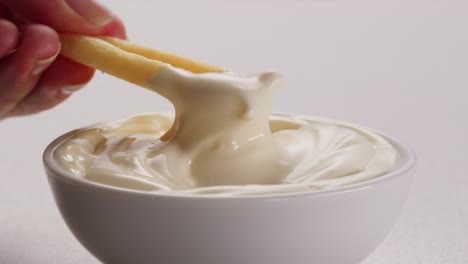 hand dipping french fries into mayonnaise