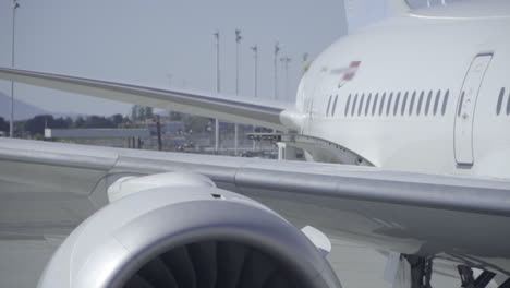 close up of airplane exhaust and jet turbine spinning while plane is parked at terminal