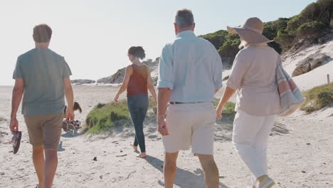 multi-generation family on summer vacation walking along sandy path on way to beach