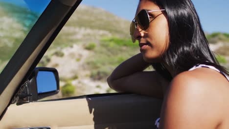 african american woman wearing sunglasses sitting in the convertible car on road