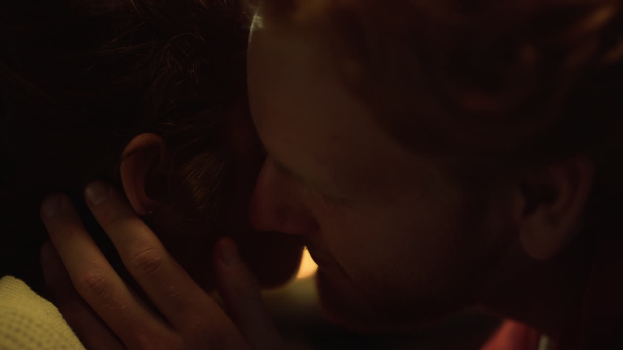 Couple faces kissing lovely together at fireplace. Two lovers express intimacy.