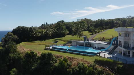 Aerial-shot-of-a-large-luxurious-private-resort-on-the-side-of-a-cliff-surrounded-by-lush-green-foliage