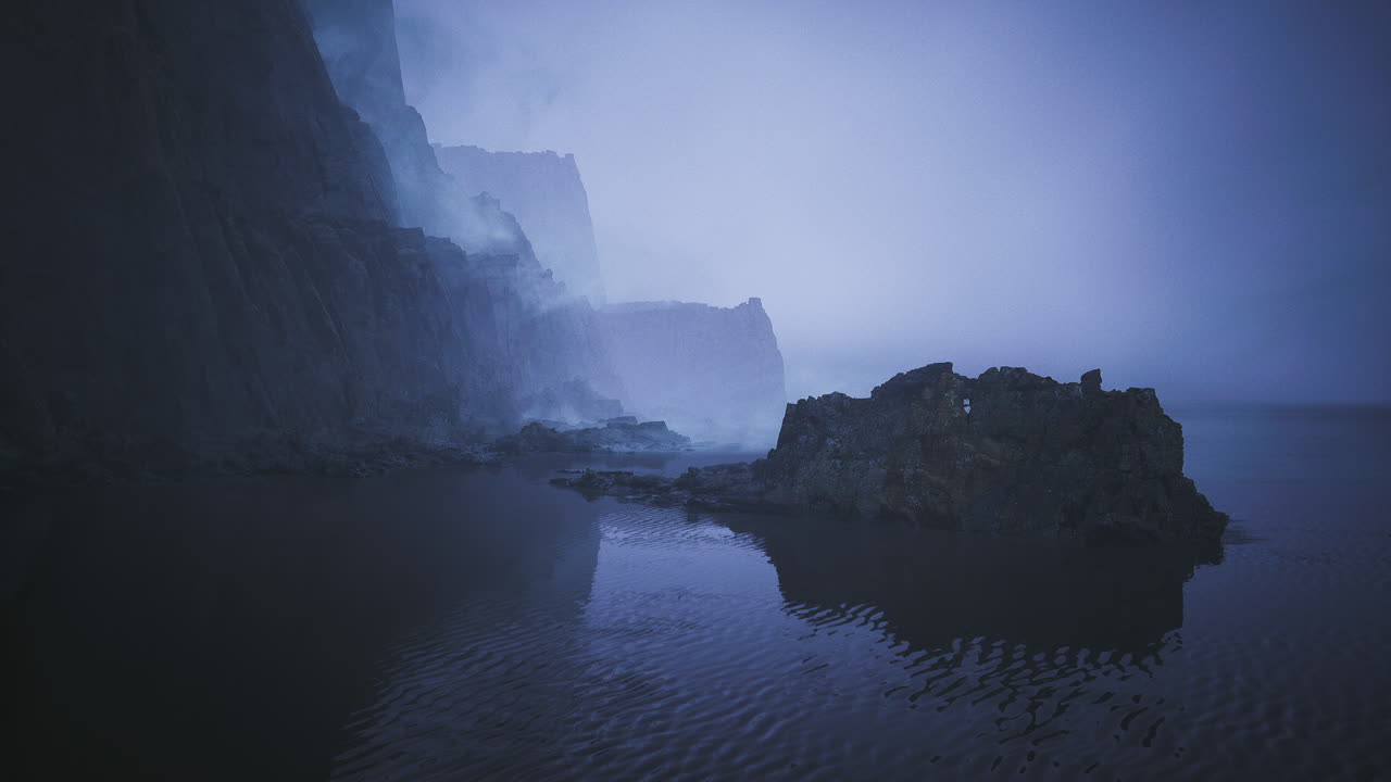 Misty cliffs with rocky shoreline and calm waters at twilight