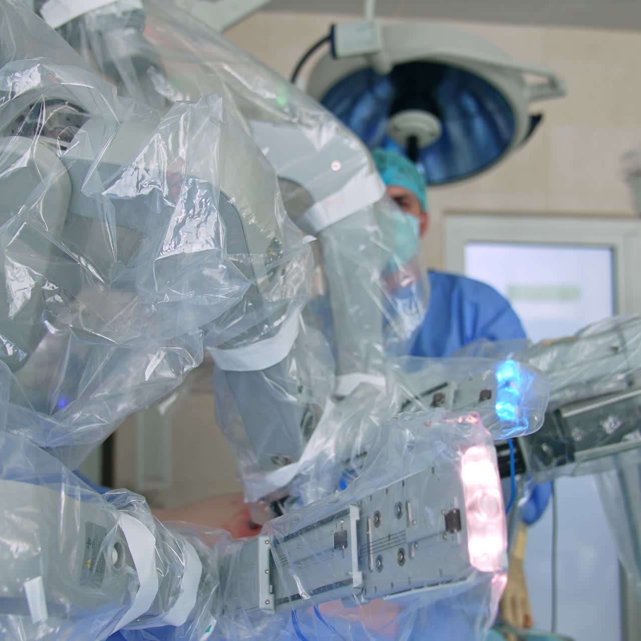 Futuristic Da Vinci robot working in the modern surgery room. Medics at backdrop watching the process of operation. Blurred backdrop