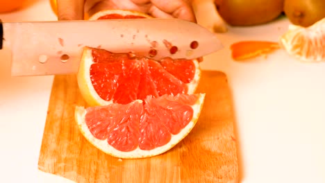 the hands of the women are using knife sliced a grapefruit.