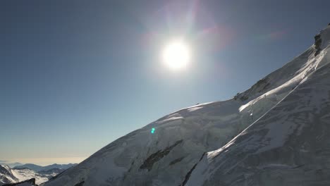 Luftpanorama:-Eisige-Steile-Bergfassade-Mit-Der-Sonne-Dahinter-Im-Winter