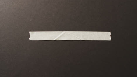 Video-of-close-up-of-white-paper-tape-piece-on-black-background