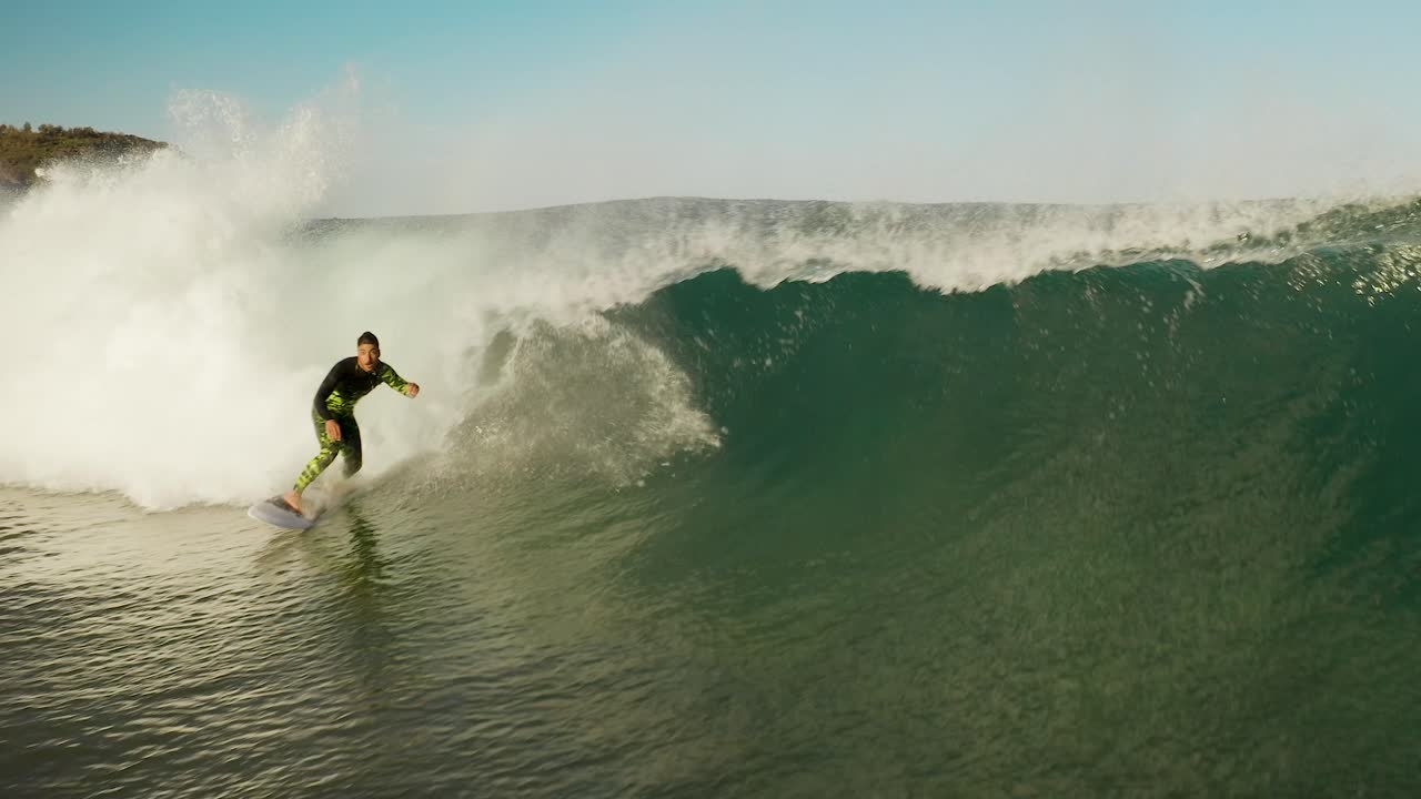 Surfer rides powerful ocean wave at sunset in slowmo. Aerial close up surfing barrel wave on coast of Sydney, Australia